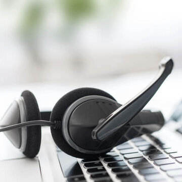 Ein Headset liegt auf der Tastatur eines Laptops