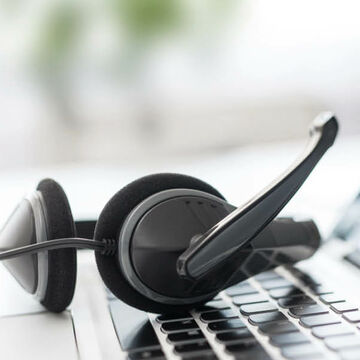 Ein Headset liegt auf der Tastatur eines Laptops