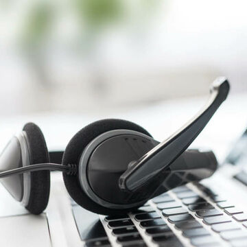 Ein Headset liegt auf der Tastatur eines Laptops